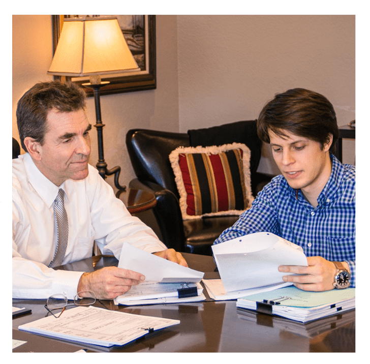 A man and woman sitting at a table with papers.