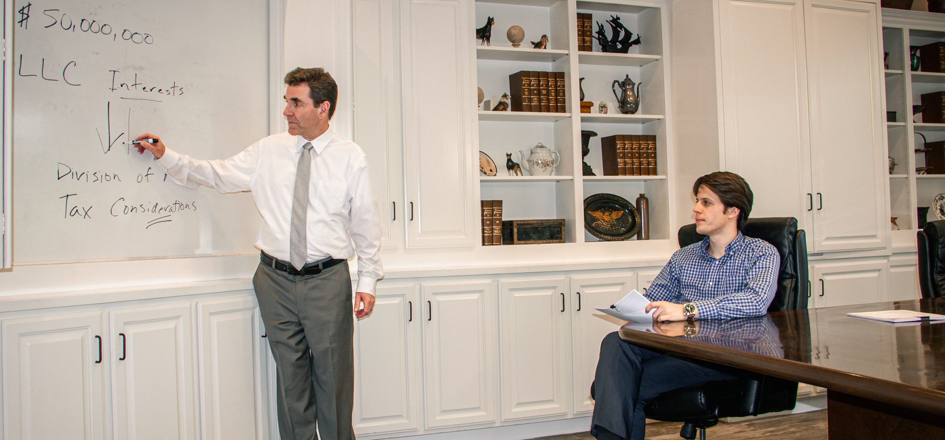 Two men in a room with white cabinets and shelves.